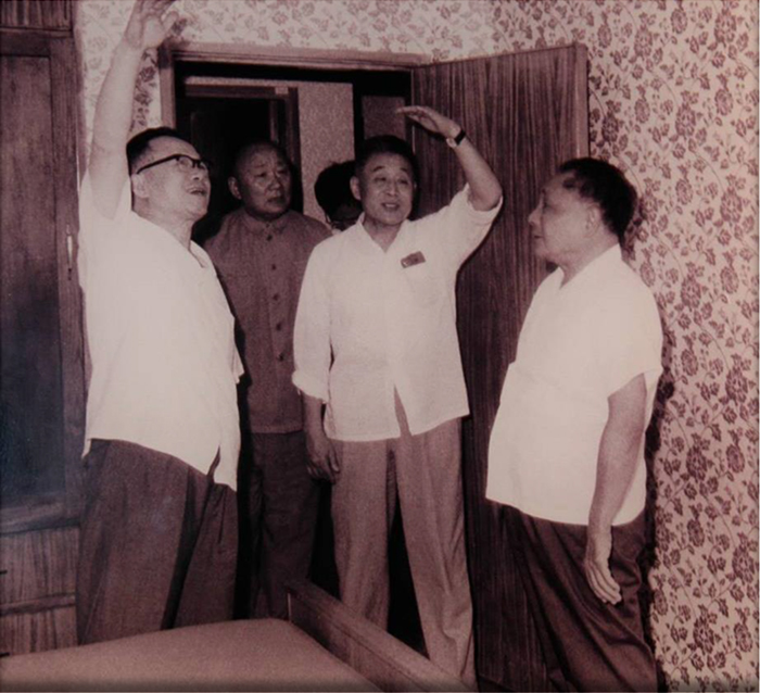 A photo of Deng Xiaoping and Gu Mu inspecting BNBM’s experimental site for new building materials. In the photo there are also other people who were working at the construction site.