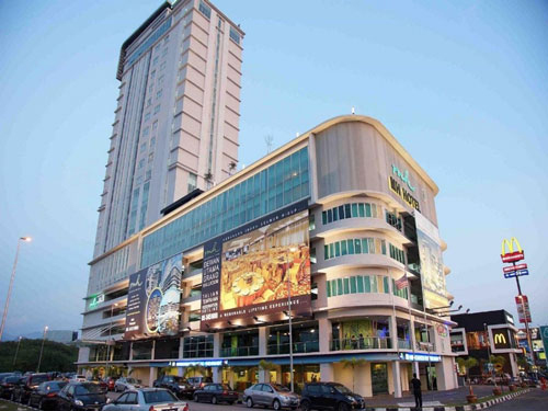 A photo shows the side view of the MH Tower hotel taken from outside. Various cars and hoardings outside the building are visible in the photo.