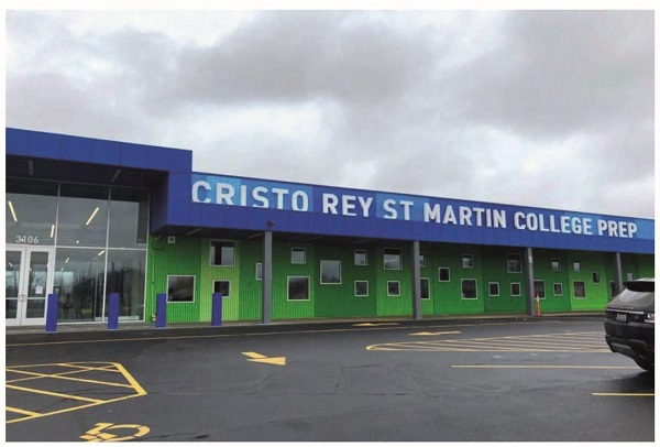 An image shows the outside view of a building labeled “CRISTO REY ST MARTIN COLLEGE PREP”. Several pavement markings are on the road outside the building. A board with label “3106” is visible through a glass door of the building.
